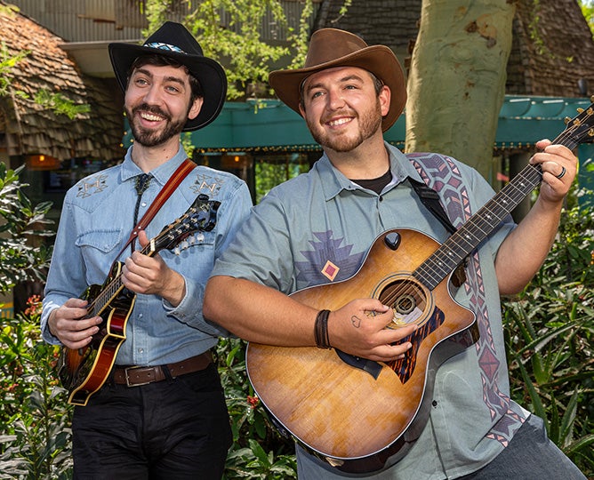 two people in blue button up shirts smiling and holding instruments