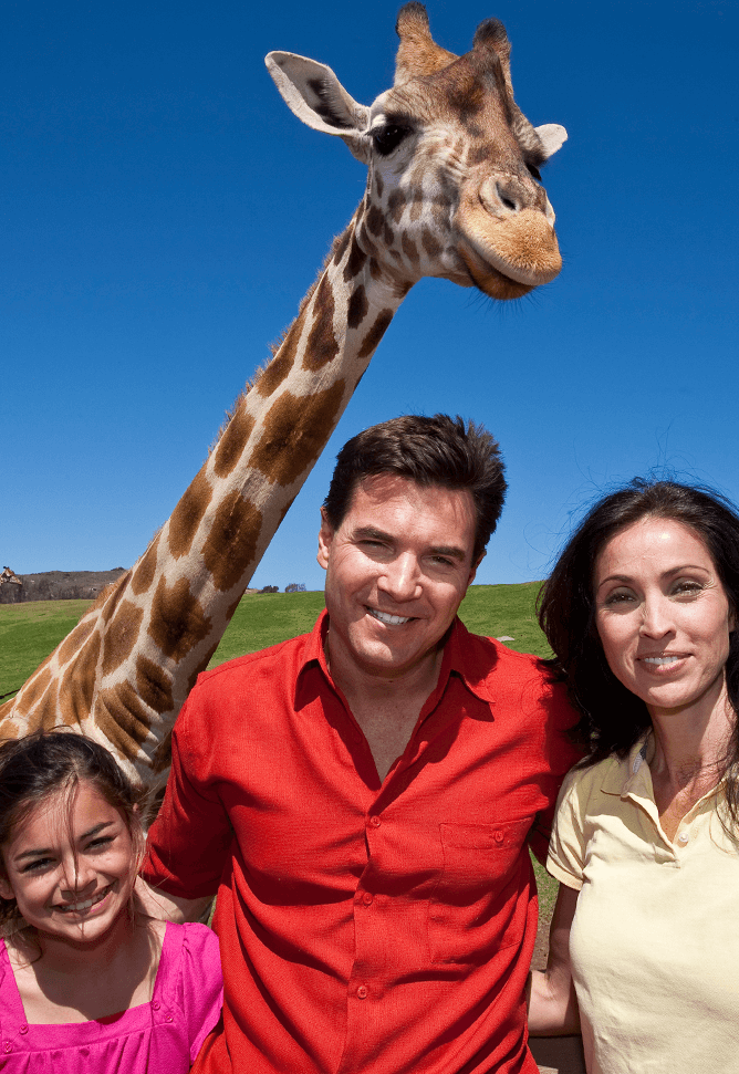 Family on wildlife safari with giraffe in background. 
